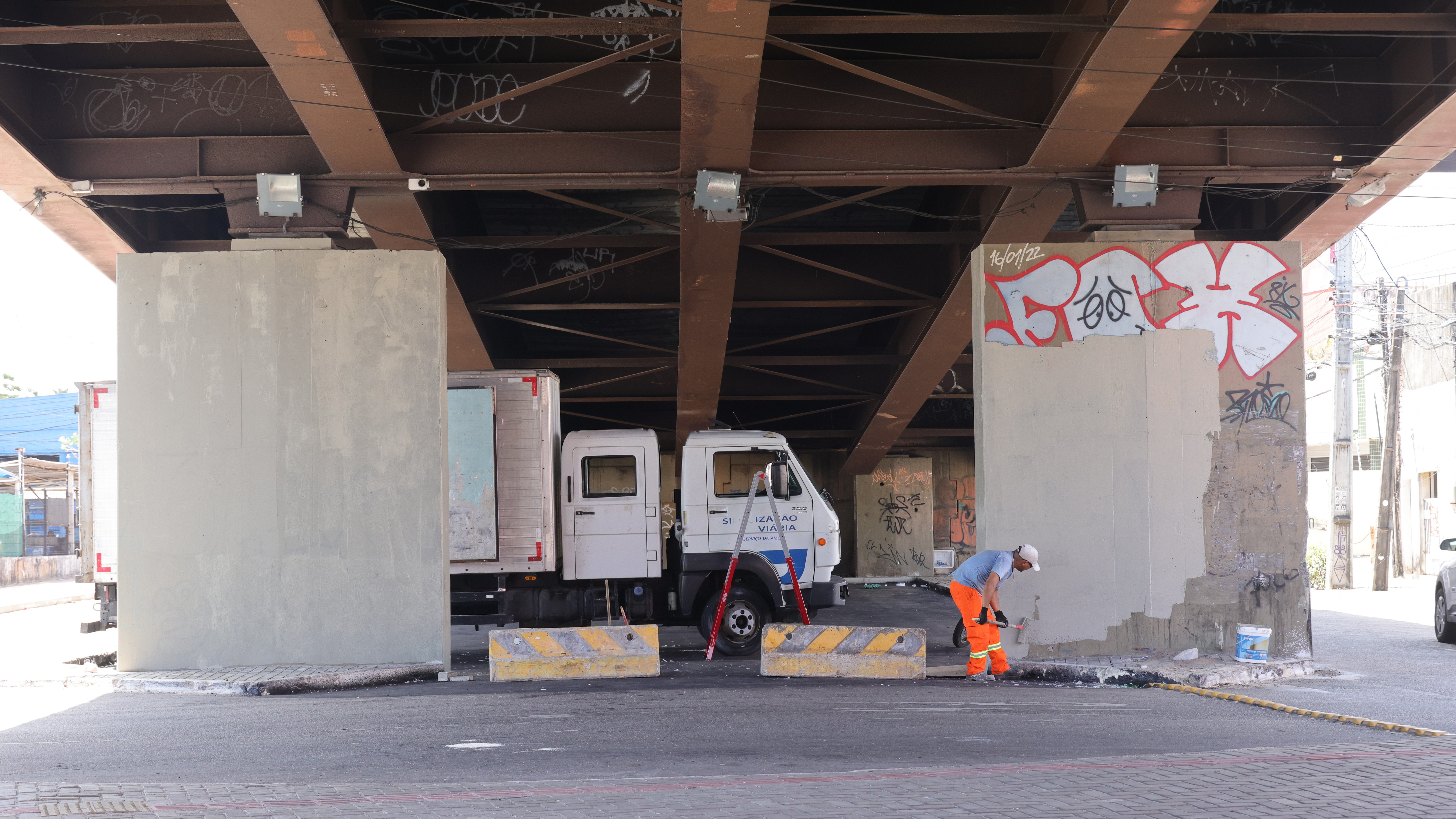 imagem mostra a parte inferior do viaduto com operários realizando pintura