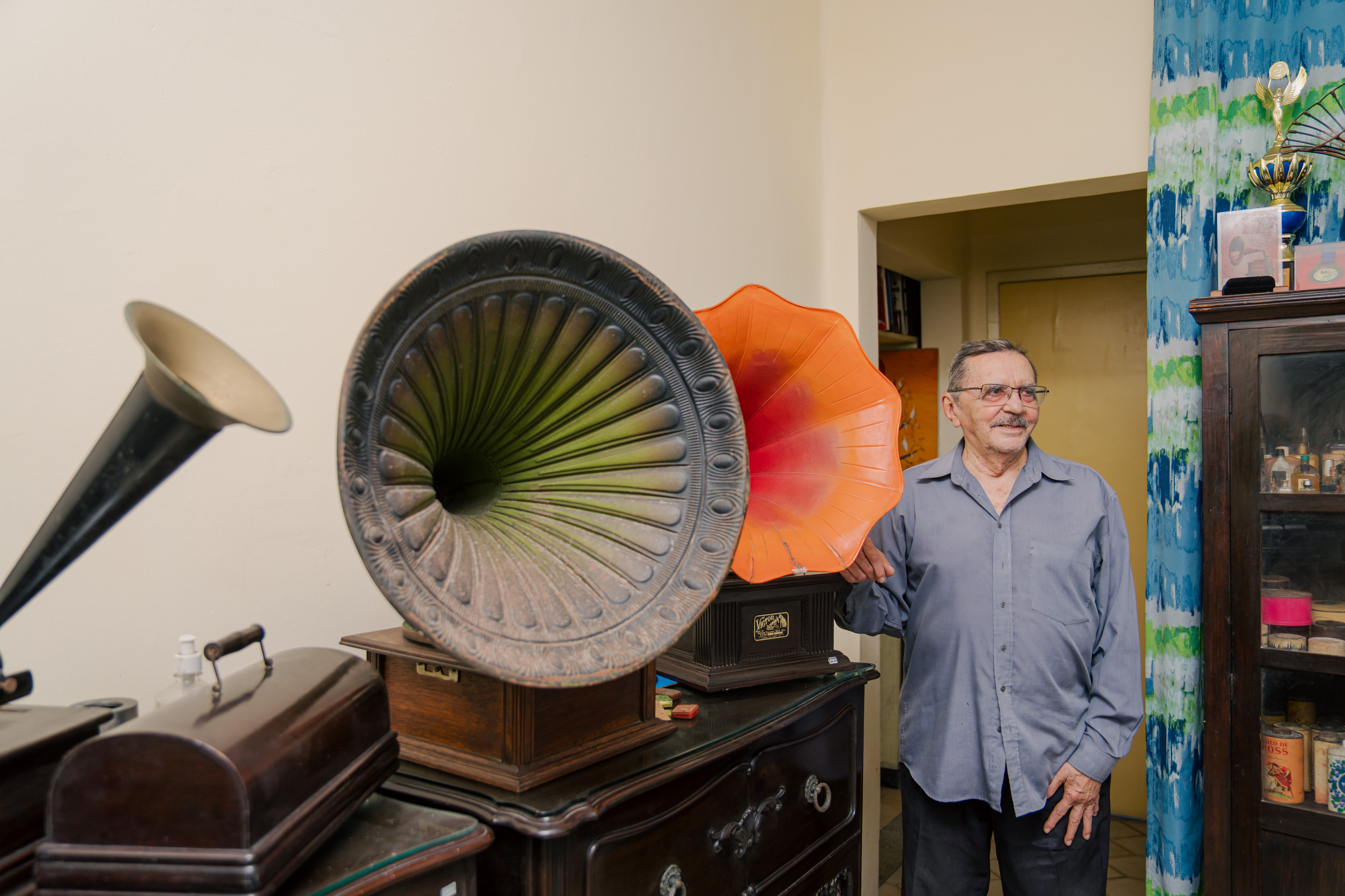 Nirez ao lado de dois gramofones numa das salas de sua casa