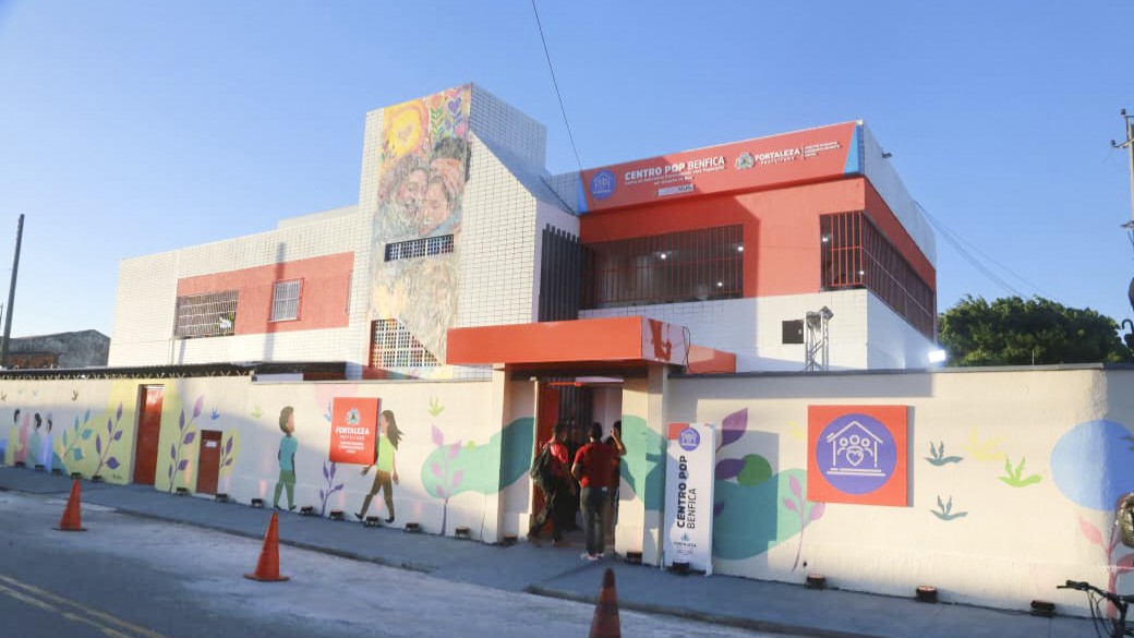 A foto mostra a fachada do Centro Pop Benfica requalificado. É um equipamento grande e ele tem pinturas coloridas e grafites