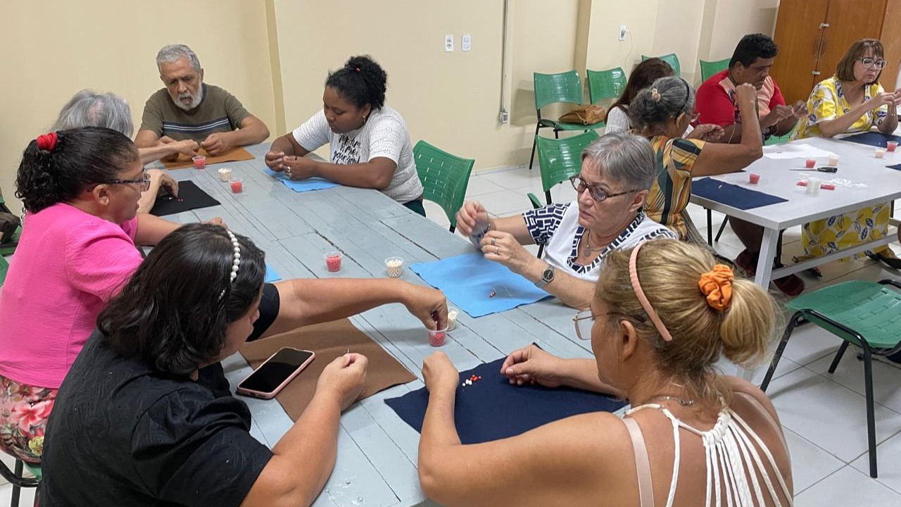 grupo de pessoas ao redor de uma mesa fazendo atividades manuais