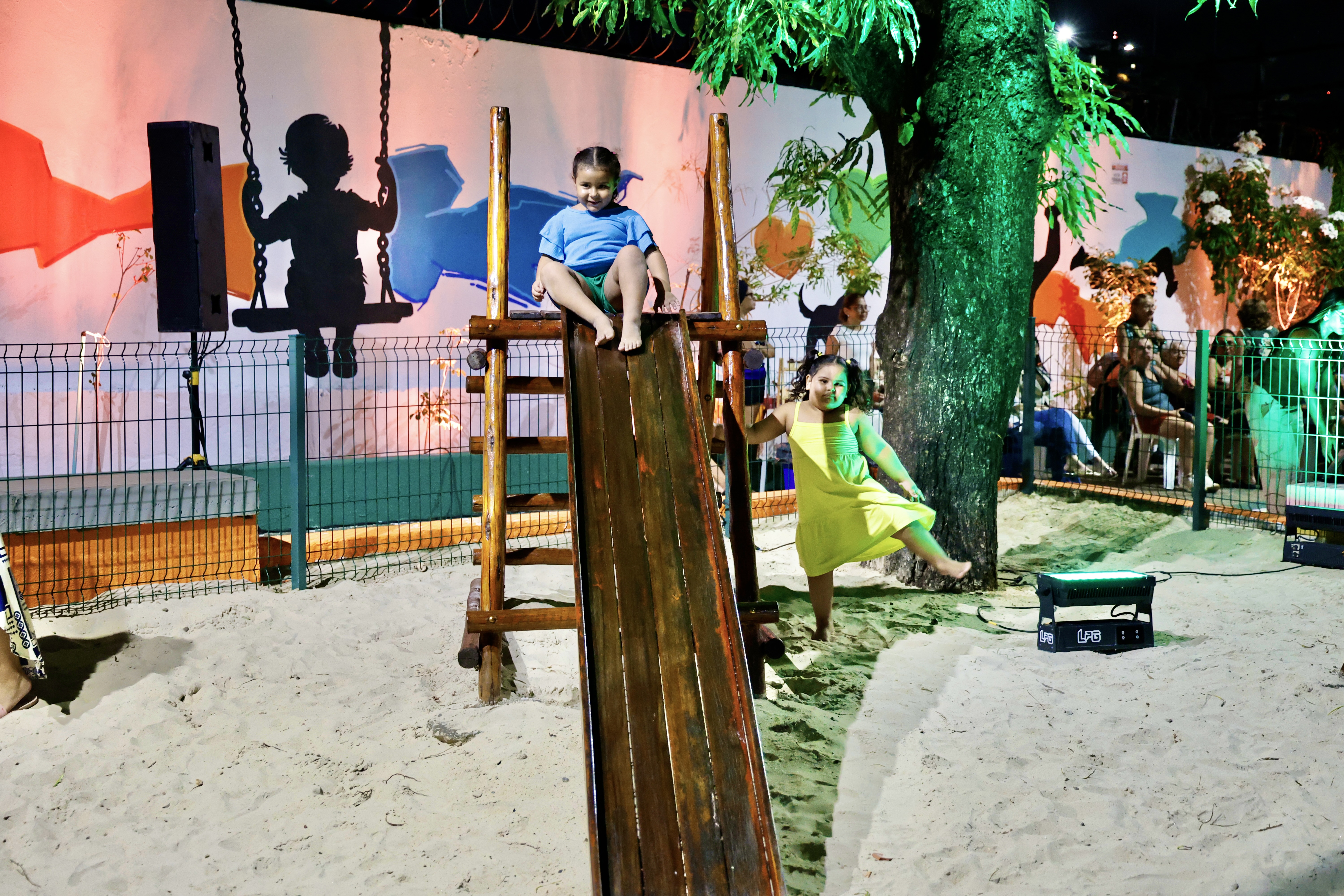 Duas meninas brincando num escorregador na praç
